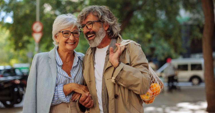 A retireed couple walk hand-in-hand together.