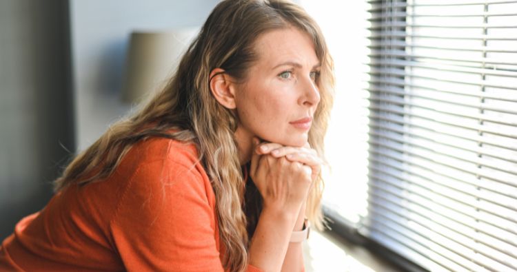 An woman looks somberly out of a window