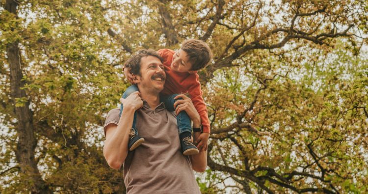 A father carrying his child on his back outdoors.